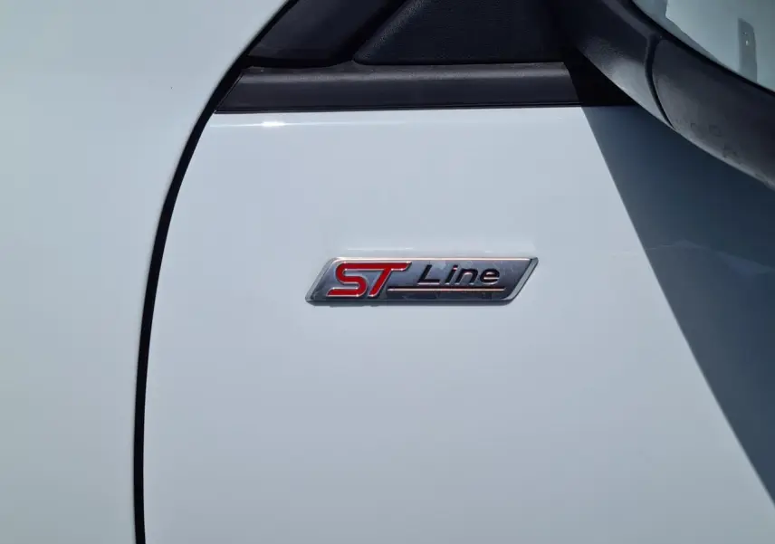 Gros plan sur l'écusson ST-Line rouge et noir sur la porte blanche glacier d'un Ford Kuga hybride rechargeable.