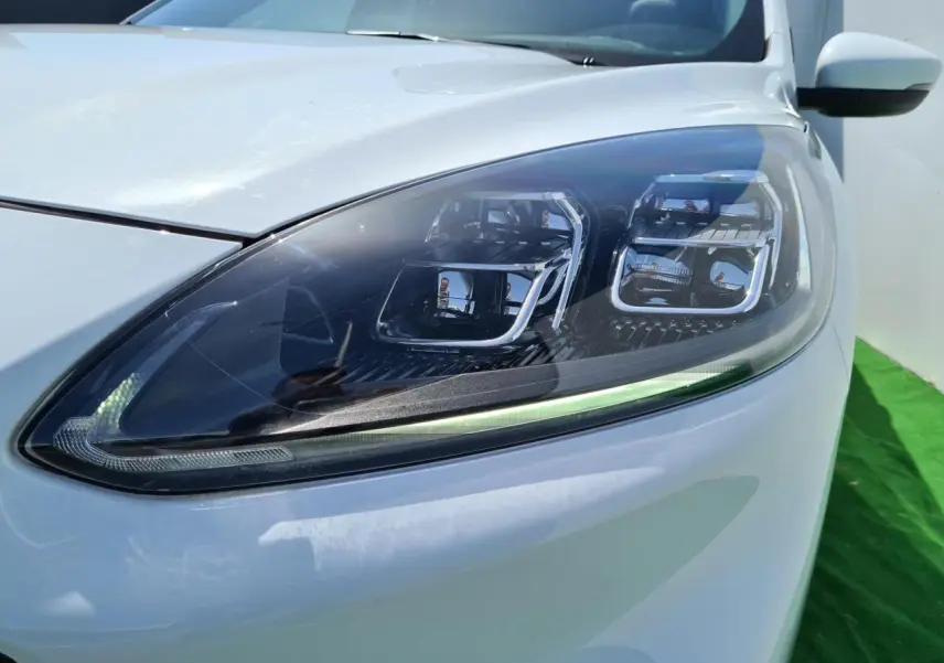 Gros plan sur le phare avant droit du Ford Kuga blanc glacier, mettant en valeur son design LED moderne.