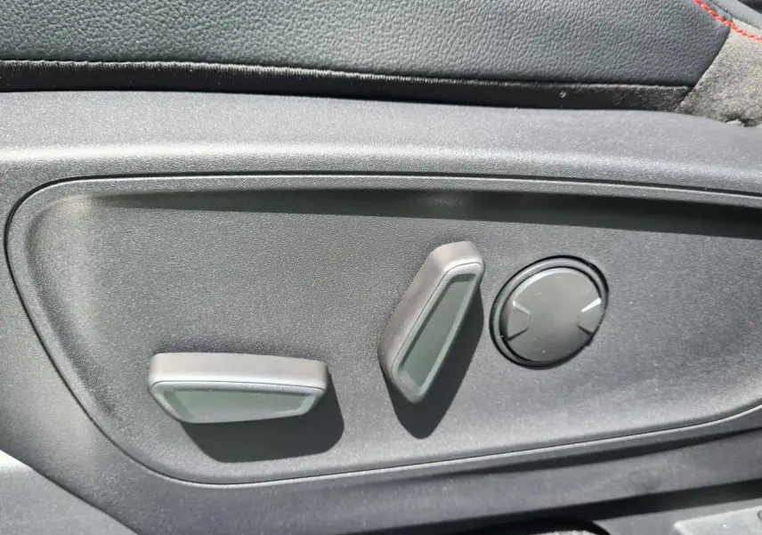 Gros plan sur les commandes électriques de réglage du siège avant côté conducteur du Ford Kuga blanc glacier 2022.