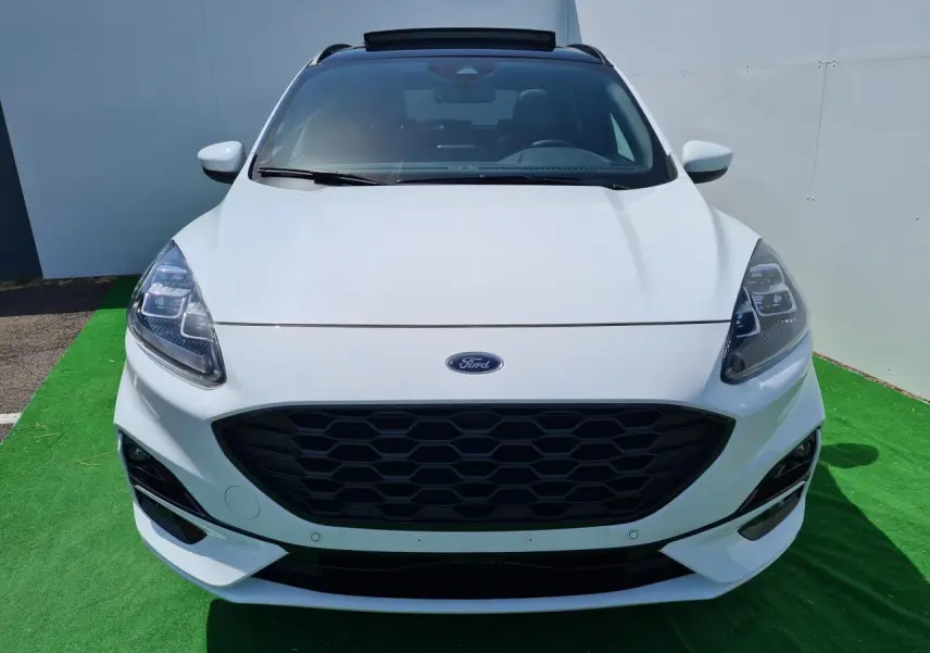 Vue frontale d'un Ford Kuga blanc glacier avec calandre noire hexagonale et phares LED distinctifs.