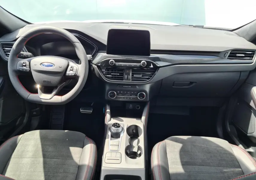 Intérieur avant du Ford Kuga blanc glacier 2022, tableau de bord moderne avec écran tactile et volant sport à surpiqûres rouges.