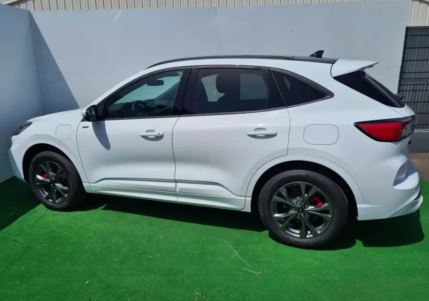 Profil côté gauche du Ford Kuga blanc glacier 2022 avec jantes alliage noires et étriers rouges visibles.