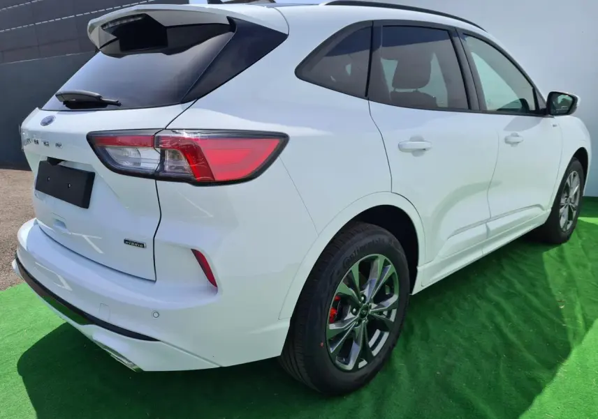 Vue 3/4 arrière droite d'un Ford Kuga blanc glacier hybride rechargeable avec jantes alliage et feux LED distinctifs.