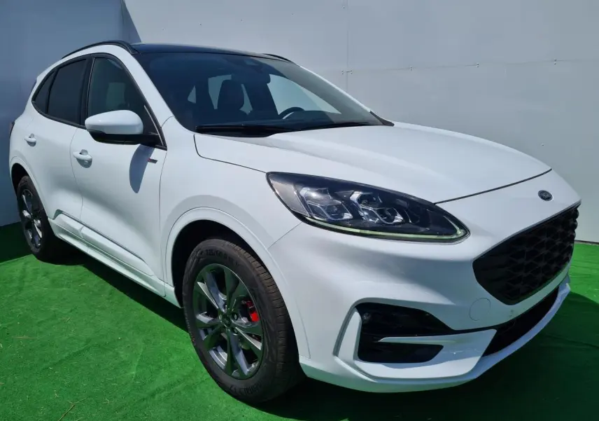 Ford Kuga blanc glacier en 3/4 avant droit avec jantes alliage et calandre noire ST-Line visible.