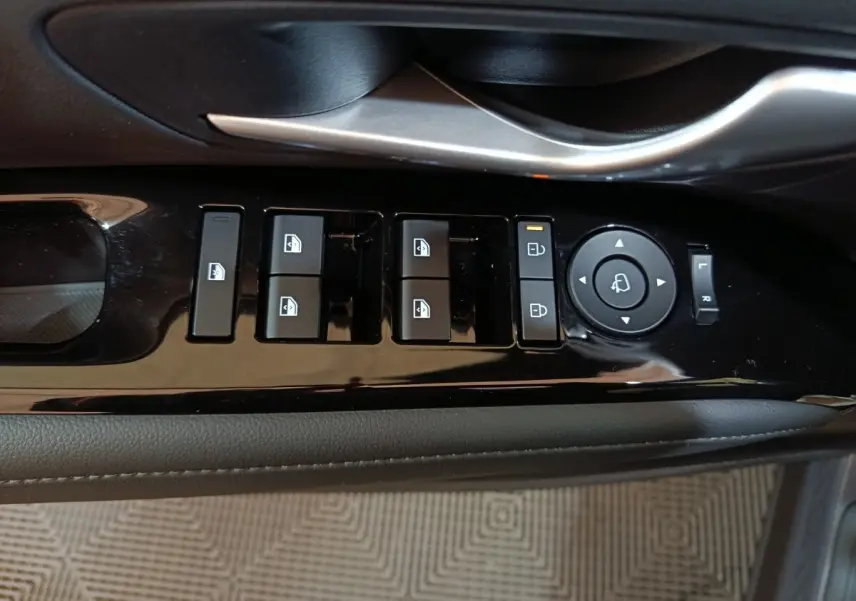 Gros plan sur les commandes de lève-vitres et rétroviseurs côté conducteur du Hyundai Tucson gris foncé 2025.