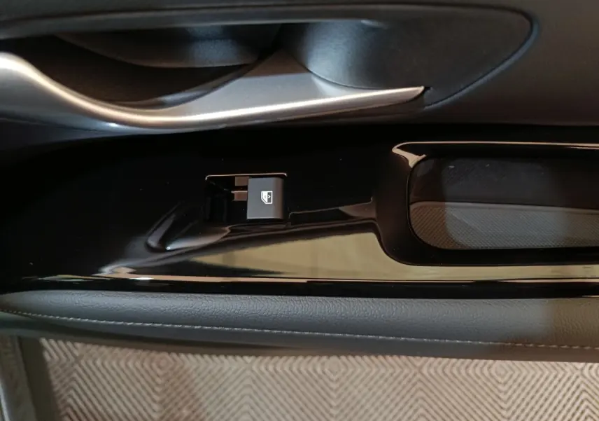 Gros plan sur la commande de lève-vitre côté conducteur dans l'intérieur noir brillant du Hyundai Tucson gris foncé.