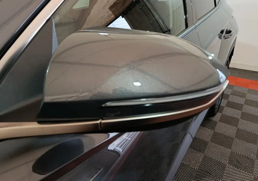 Rétroviseur droit gris foncé du Hyundai Tucson 2025, vue rapprochée avec partie latérale arrière du véhicule visible.
