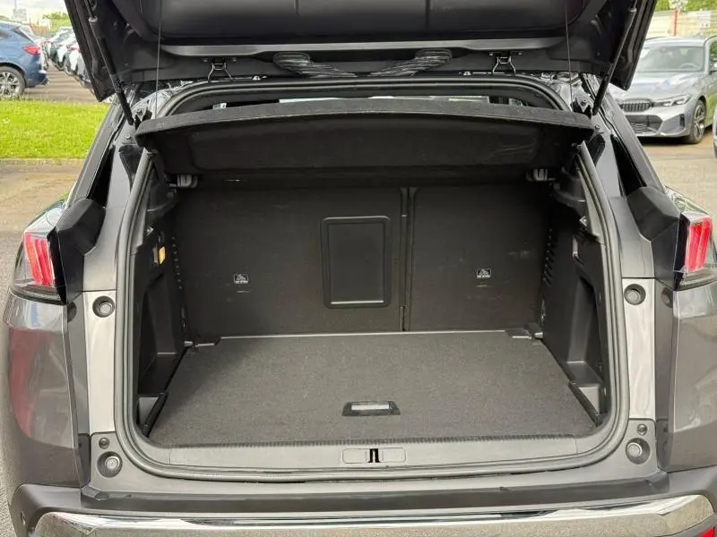 Coffre ouvert vu de l'arrière d'un Peugeot 3008 gris Platinium, montrant l'espace de chargement vide et la trappe à skis.