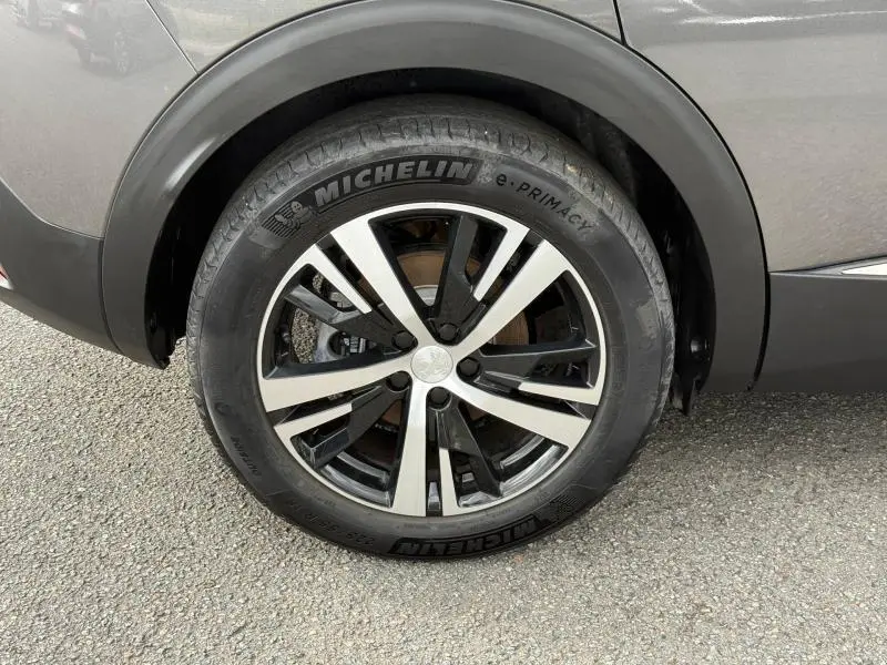 Gros plan sur la roue avant droite du Peugeot 3008 Gris Platinium avec jante alu bicolore et pneu Michelin.