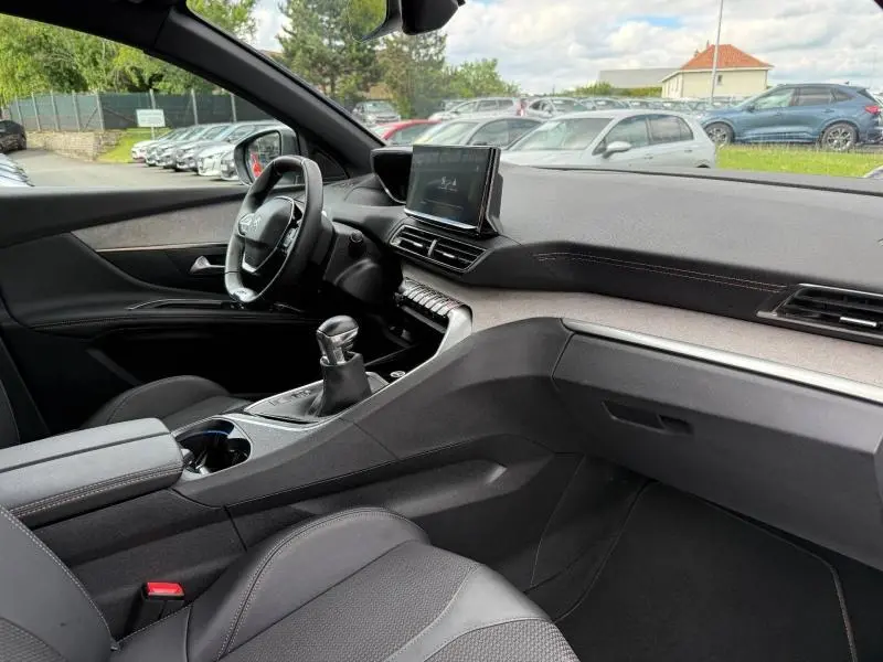 Vue intérieure côté conducteur du Peugeot 3008 2024, montrant le volant cuir multifonction et la console centrale avec boîte manuelle.
