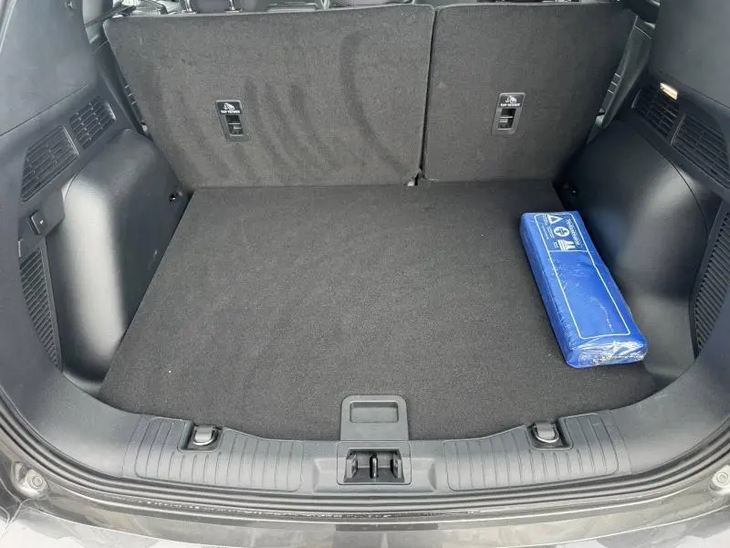 Coffre ouvert du Ford Kuga gris Solar Métallisé 2023, montrant un espace de chargement propre avec un kit de sécurité bleu.