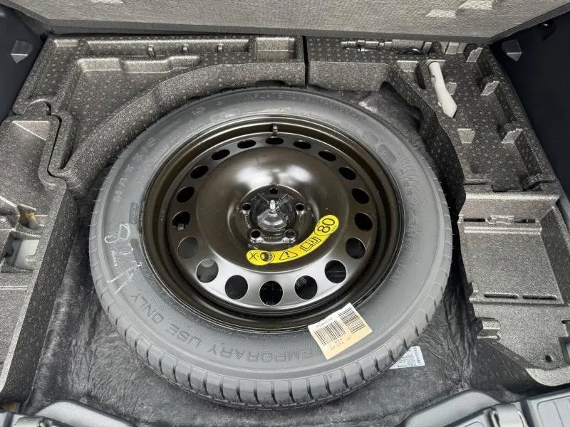 Vue rapprochée de la roue de secours noire dans le coffre du Ford Kuga gris Solar Métallisée 2023.