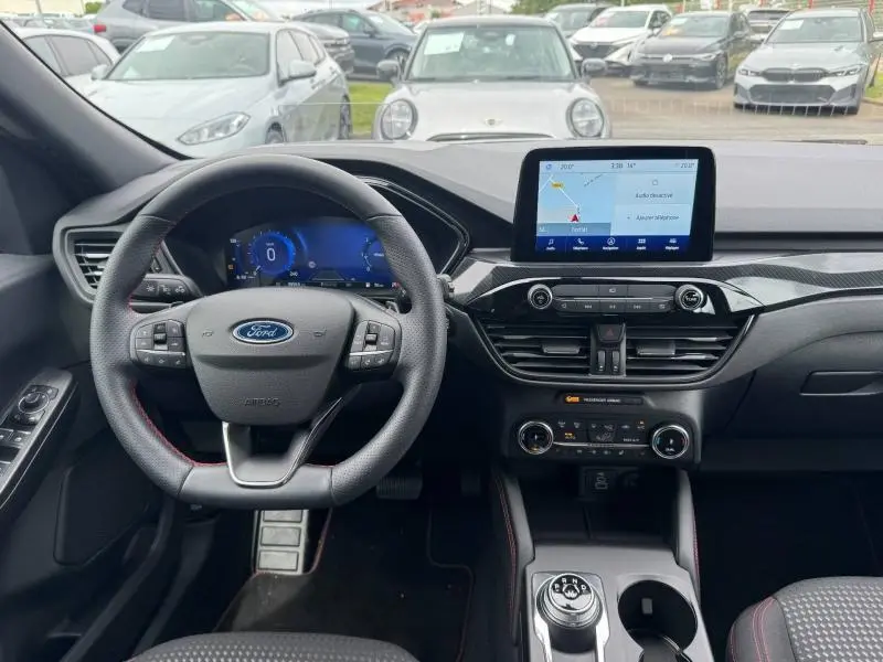 Vue intérieure avant du Ford Kuga 1.5 EcoBlue 2023, tableau de bord noir avec écran tactile et volant cuir multifonction.