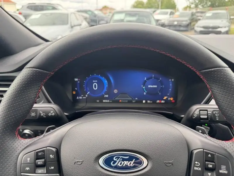 Vue depuis le siège conducteur du tableau de bord numérique et volant cuir perforé avec surpiqûres rouges du Ford Kuga gris Solar.