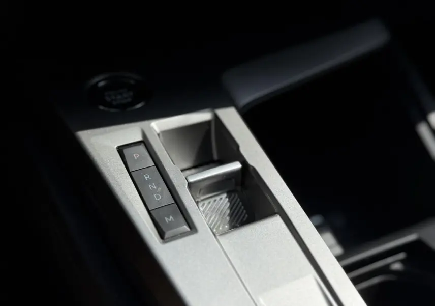 Gros plan sur la console centrale grise métallisée de la Peugeot 308 avec les boutons de la boîte auto et le frein électrique.