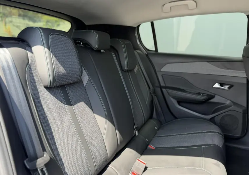 Vue intérieure côté droit des sièges arrière en tissu et cuir noir avec surpiqûres contrastantes dans une Peugeot 308 2025.