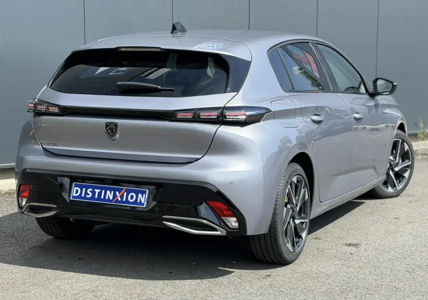 Vue 3/4 arrière droite d'une Peugeot 308 gris Artense avec jantes alliage et bandeau noir brillant entre feux arrière.