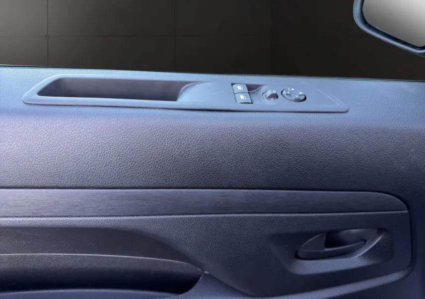 Gros plan sur la porte côté conducteur du Citroën Jumpy noir, avec commandes de vitres et rétroviseur électrique.