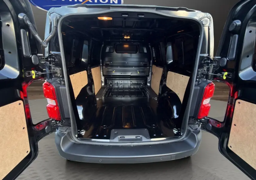 Vue arrière du Citroën Jumpy noir 2026 avec portes ouvertes montrant l'espace de chargement vide et les panneaux latéraux en bois.