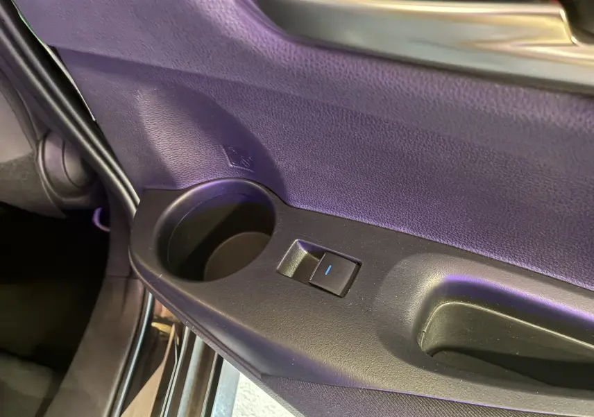 Gros plan sur la poignée intérieure et le bouton de lève-vitre côté gauche de la porte noire d'une Toyota Corolla 2020.