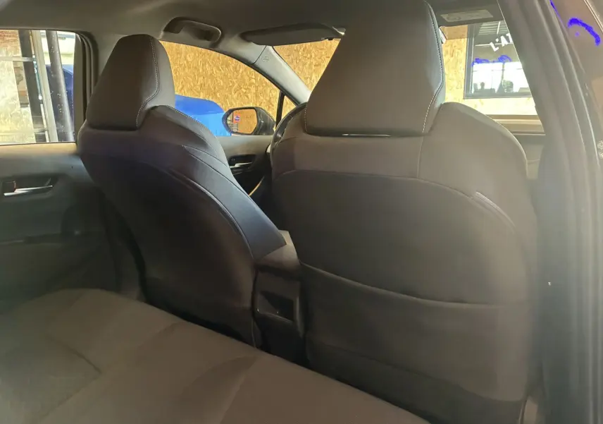 Vue intérieure arrière de la Toyota Corolla 1.8 122 Dynamic noire, montrant les sièges avant et banquette tissu noire.