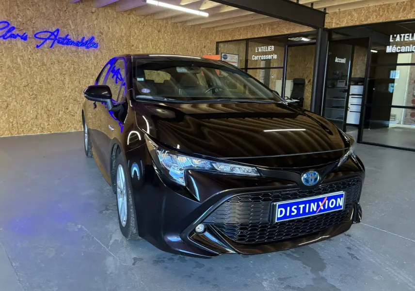 Toyota Corolla 1.8 122 Dynamic noire vue 3/4 avant droit avec calandre large et phares LED en showroom