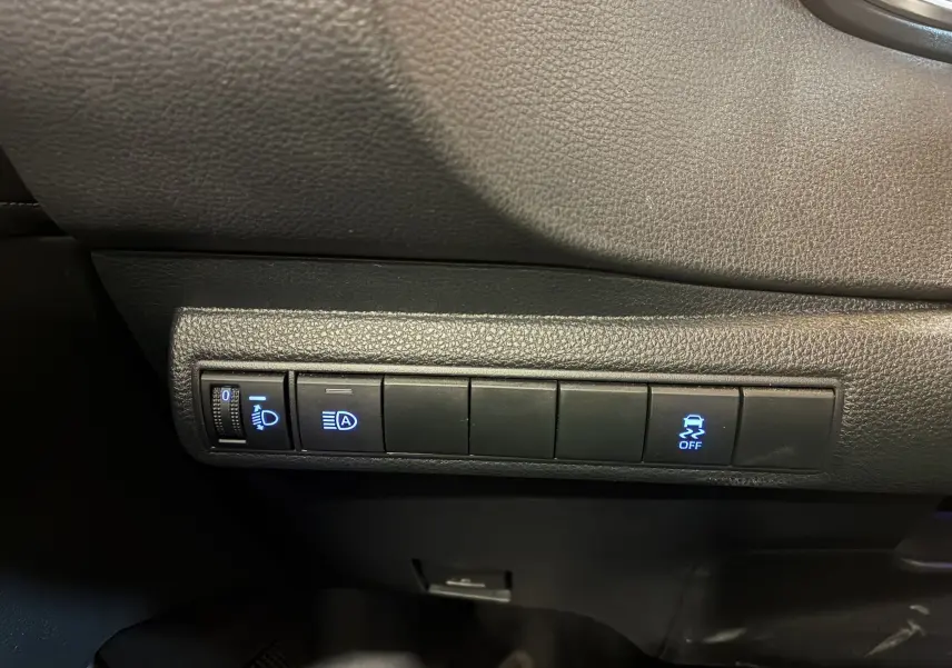 Gros plan sur les commandes noires du tableau de bord de la Toyota Corolla 1.8 122 Dynamic 2020, avec voyants bleus allumés.