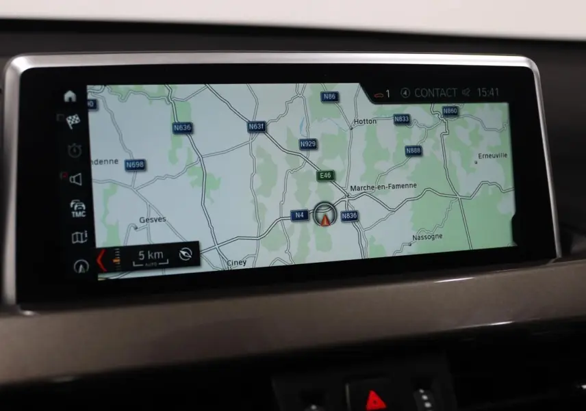 Écran de navigation GPS intégré au tableau de bord d'un BMW X1 sDrive 18D argent, affichant une carte routière.