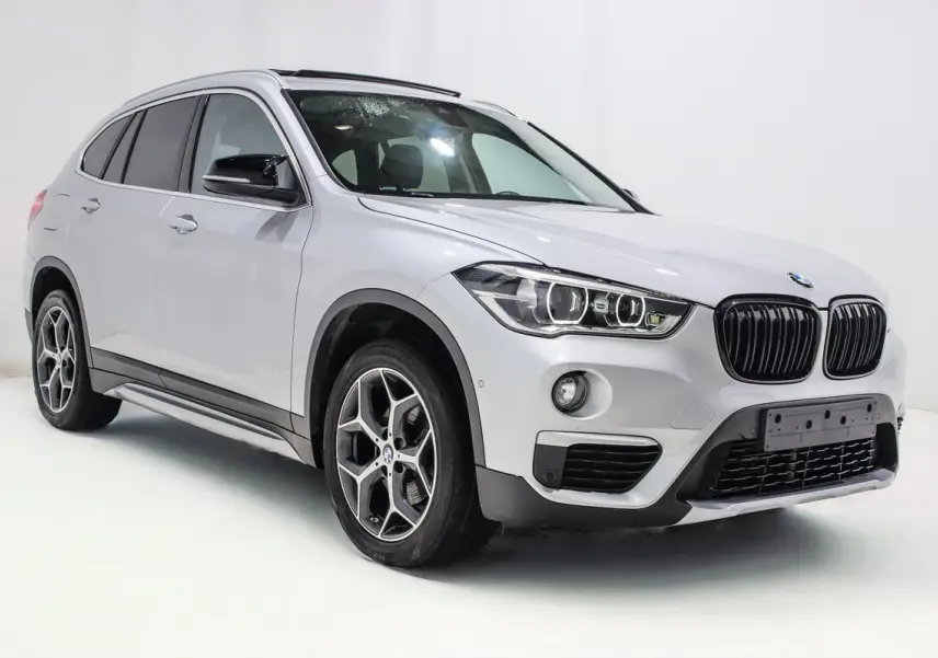 BMW X1 sDrive 18D argent métallisé en 3/4 avant droit, avec toit ouvrant et jantes alliage distinctives.