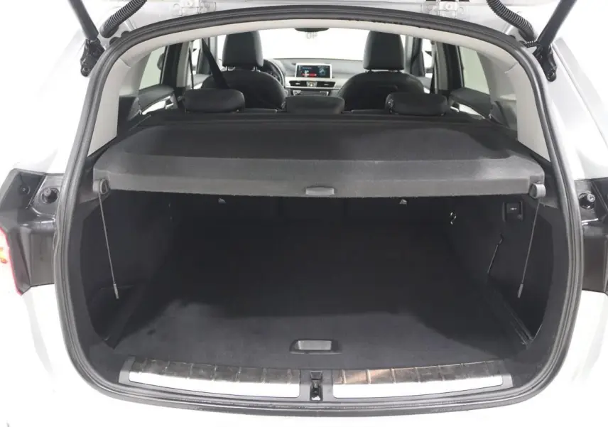 Coffre ouvert d’un BMW X1 argent métallisé vu de l’arrière, montrant l’espace de chargement et l’intérieur noir.