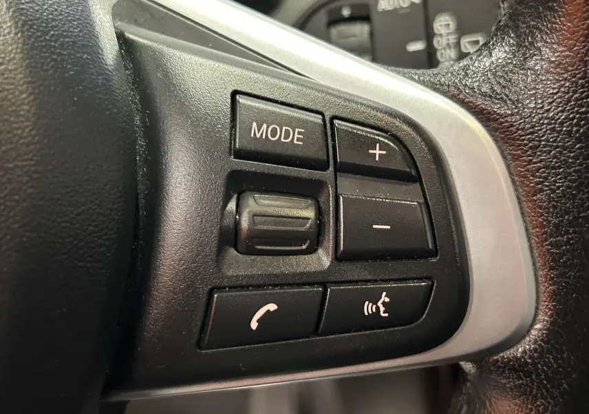 Gros plan sur les commandes au volant côté droit d’un BMW X1 2019, boutons mode, volume et téléphone.