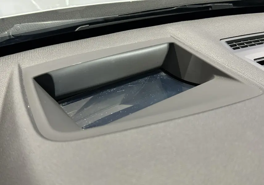 Gros plan sur l'écran escamotable du tableau de bord d'une BMW X1 argent métallisé, intérieur gris.