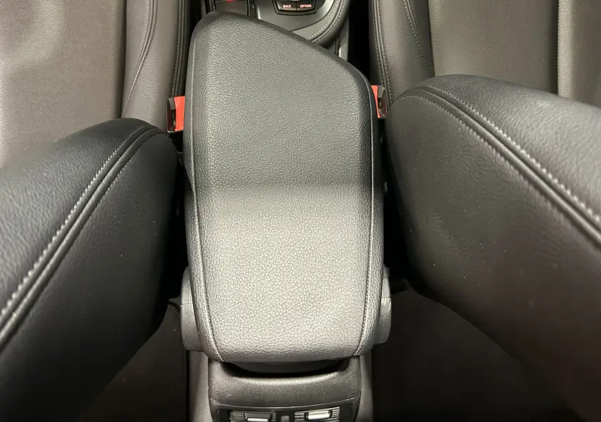 Vue rapprochée du couvercle de la console centrale en cuir noir entre les sièges avant d’un BMW X1 argent métallisé.