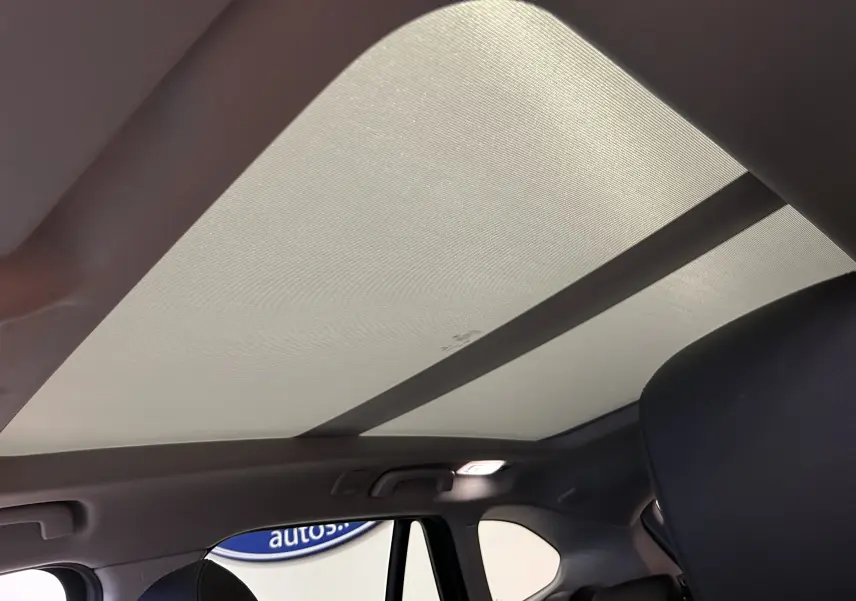 Vue intérieure du toit ouvrant fermé sur BMW X1 sDrive 18D argent métallisé, montrant la partie arrière des sièges noirs.