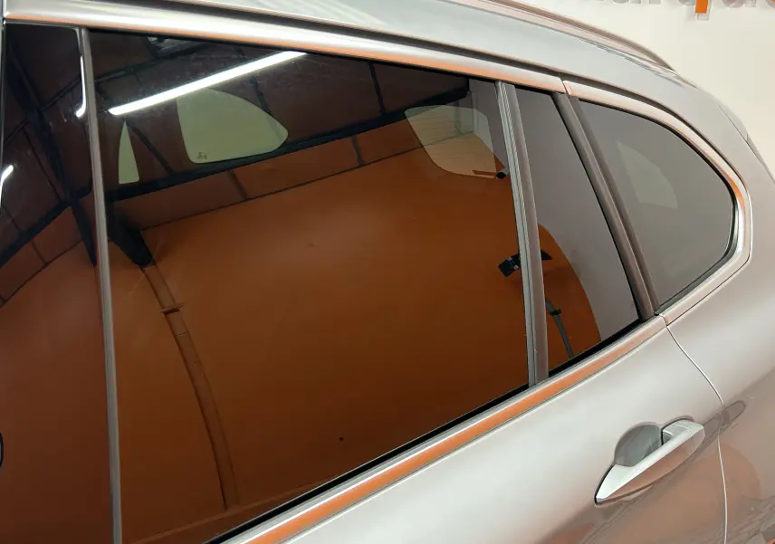 Vue latérale côté droit d’un BMW X1 sDrive 18D argent métallisé avec vitres teintées et poignée de porte visible.