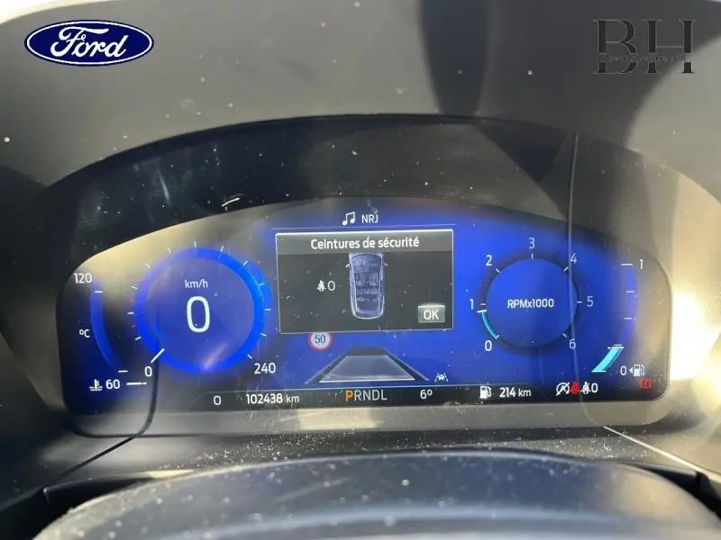 Vue rapprochée du tableau de bord numérique du Ford Kuga 2020 avec affichage bleu et informations de conduite.