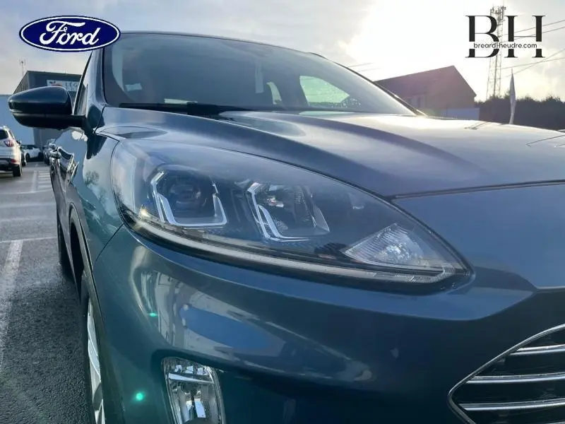 Vue en gros plan 3/4 avant gauche du Ford Kuga bleu azur métallisé mettant en valeur ses phares avant LED et la calandre chromée.