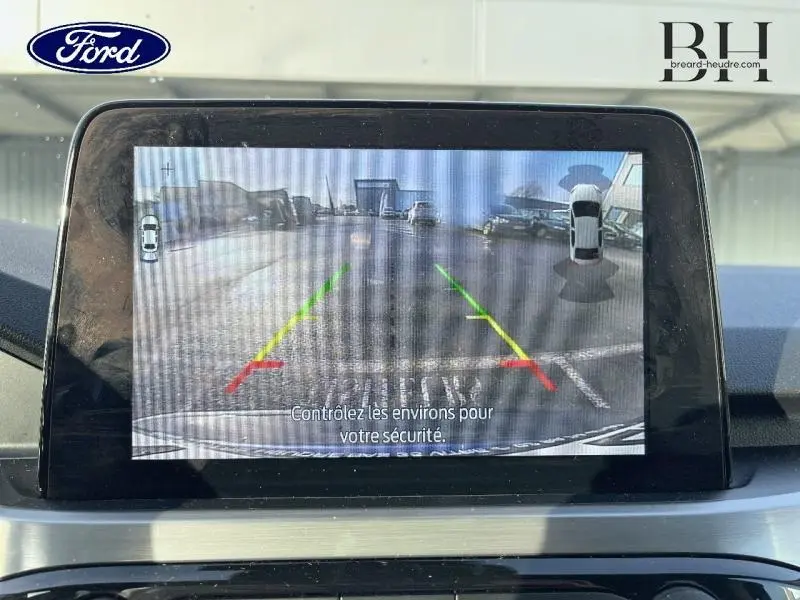 Écran tactile intérieur du Ford Kuga 2020 montrant la caméra de recul avec lignes de guidage colorées.