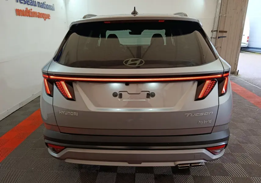 Vue arrière d'un Hyundai Tucson gris clair 2025 avec feux LED distinctifs et logo Hyundai visible sur le hayon.