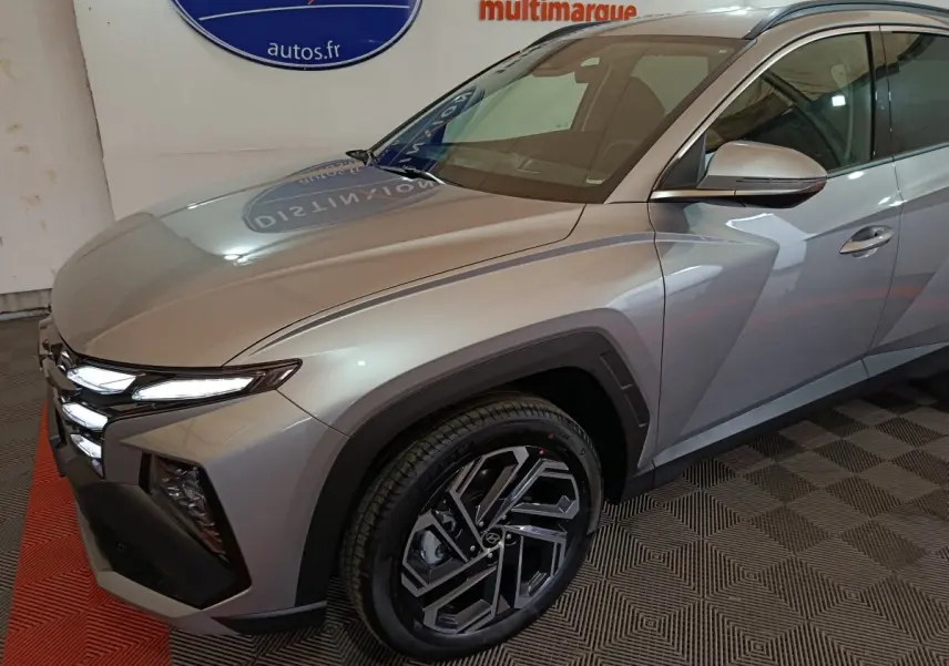 Vue 3/4 avant droit du Hyundai Tucson 2025 gris clair avec phares LED et jantes alliage distinctives.