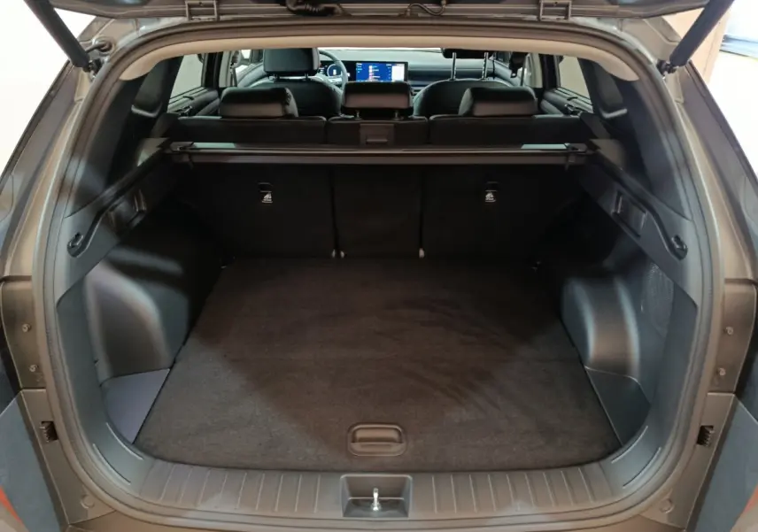 Coffre ouvert du Hyundai Tucson gris clair 2025, vue arrière montrant l’espace de chargement et la banquette arrière.