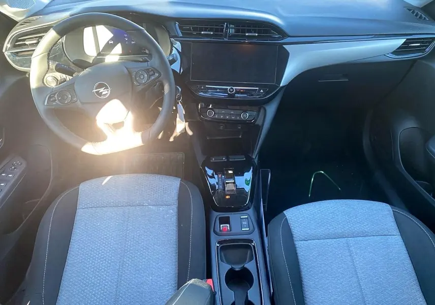 Vue intérieure avant de l'Opel Corsa 2025 avec tableau de bord noir, volant multifonction et sièges tissu gris.