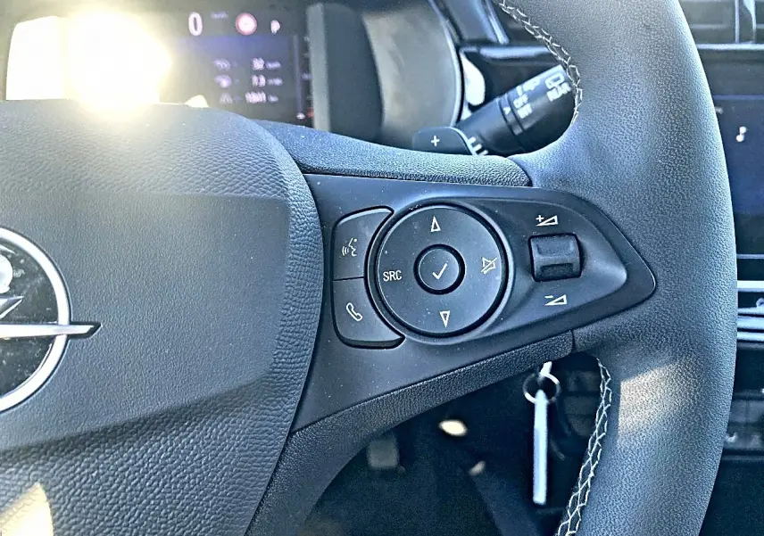 Gros plan sur le volant noir multifonction de l’Opel Corsa 2025 avec commandes audio et logo central visible.