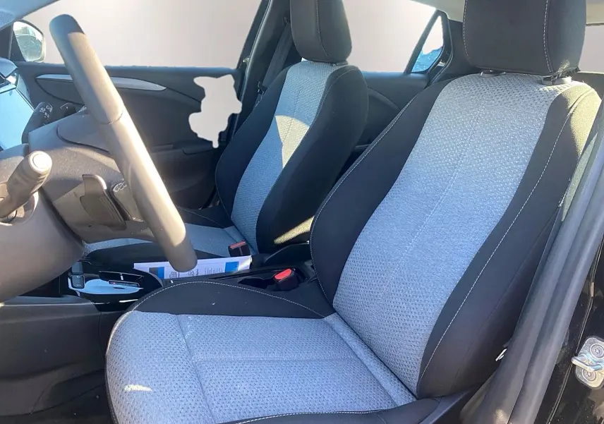 Vue intérieure côté conducteur de l'Opel Corsa 2025, sièges tissu bicolore gris et noir avec volant multifonction.