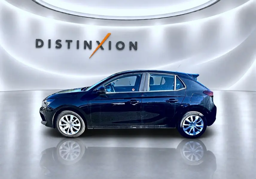 Profil côté gauche d'une Opel Corsa noire 2025 dans un showroom lumineux avec jantes argentées et becquet arrière.