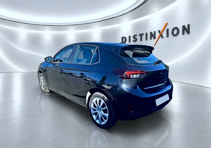 Opel Corsa noire vue 3/4 arrière droit dans un showroom avec becquet et jantes alliage visibles.