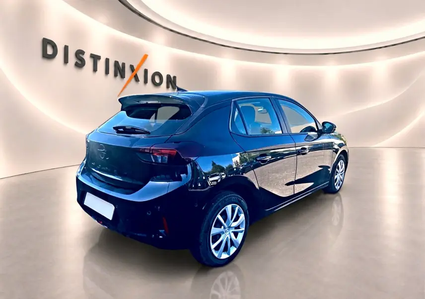 Opel Corsa noire vue 3/4 arrière droit dans un showroom lumineux avec becquet et jantes alliage.