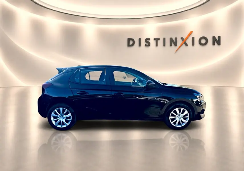 Opel Corsa noire vue de profil côté gauche, avec becquet arrière et jantes argentées dans un showroom lumineux.