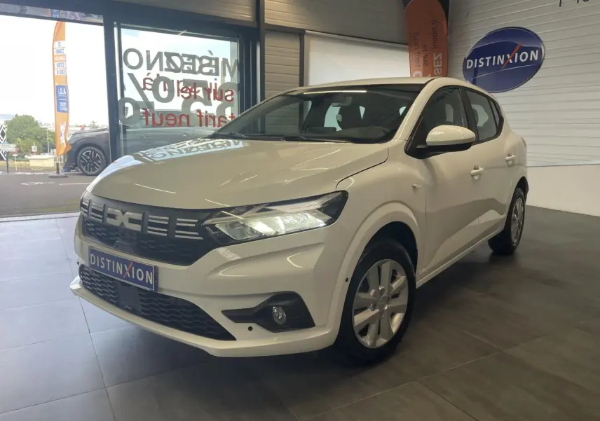 Dacia Sandero blanc vue 3/4 avant droit en showroom avec calandre noire et feux LED allumés.