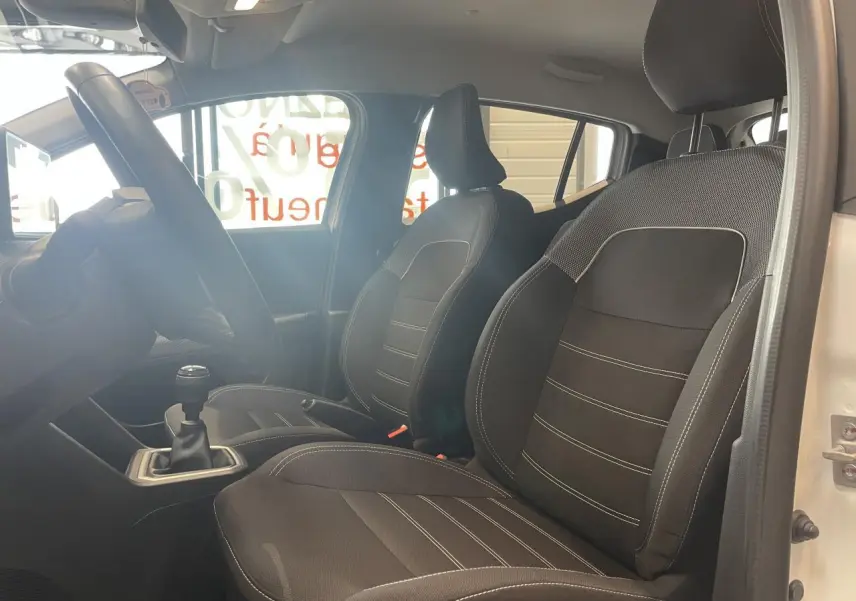 Vue intérieure côté gauche montrant les sièges avant noirs et la boîte manuelle d'une Dacia Sandero blanche 2024.
